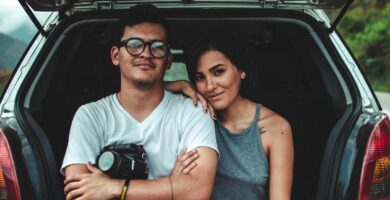 woman leaning on man's shoulder beside car during daytime